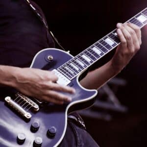 E-Gitarrenspieler auf der Bühne im Scheinwerferlicht – E-Gitarre online lernen im Rockgitarre Kurs der New Music Academy seit 1990.